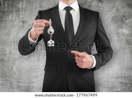businessman gives a key on a concrete wall background
