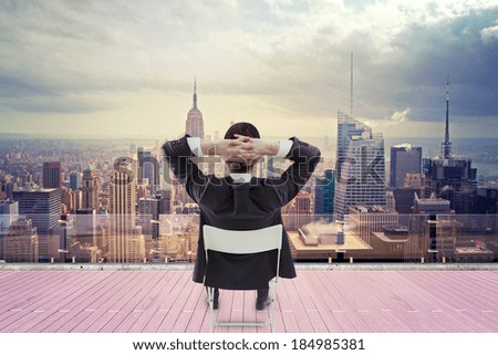 businessman sitting on roof and looking at city