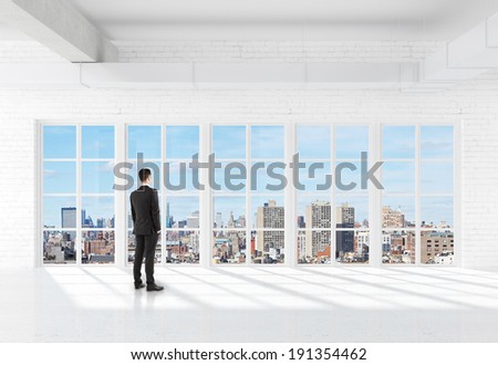 businessman in suit standing in room and looking at window
