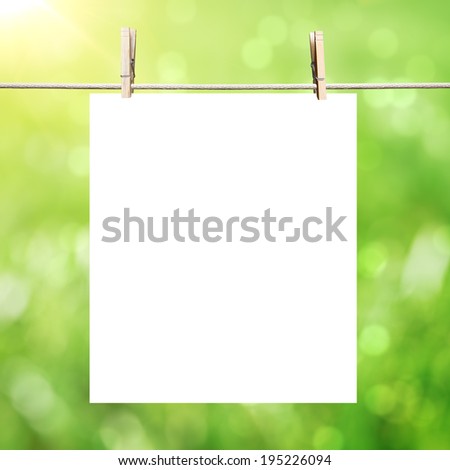 white blank paper hanging on clothespins on abstract summer background