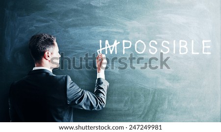businessman drawing impossible text on a blackboard