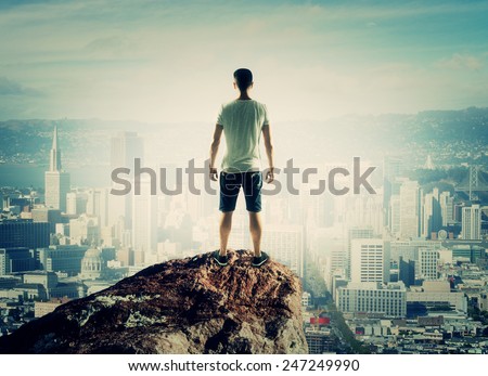 man stands on top mountain and looking to city