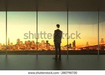 Businessman in empty office stands at the window