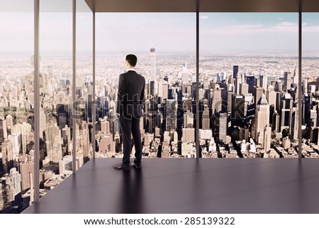 Businessman in empty office stands at the windows