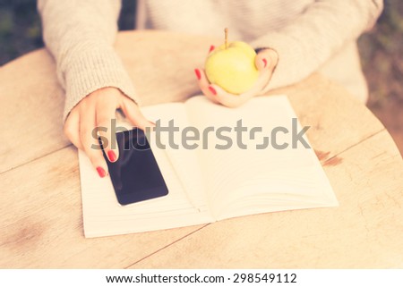 young girl with cell phone, diary and green apple, vintage photo effect