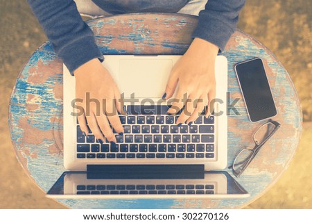 Girl sits at a table with a laptop and cell phone