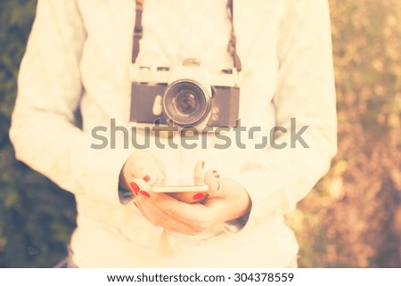 Girl with cell phone and old camera, vintage color effect