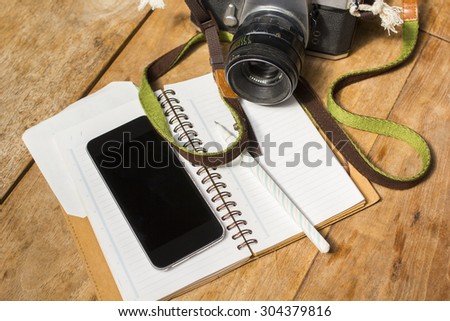 cell phone, diary and old camera on a wooden table