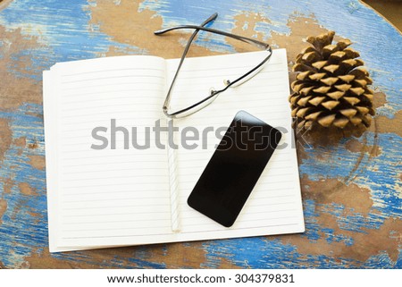 cell phone, diary and glasses on a vintage wooden table