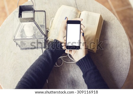 Girl with blank cell phone and books