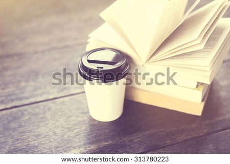 Coffee to go and pack of books on a wooden table, vintage photo effect