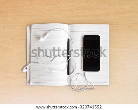 Exercise book with pen and cell phone with headphones