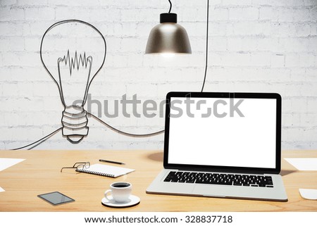 Desktop with blank laptop and light bulb on the wall, creative concept