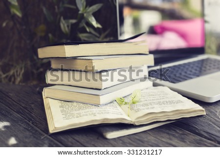 Pack of books with laptop on the wooden table outdoor