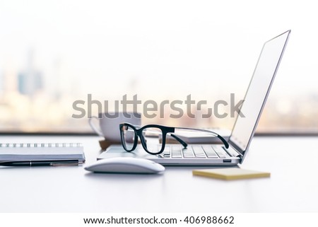Sideview of office desk with laptop, glasses and other items