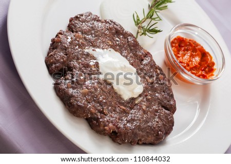 Piece of beef is served on a plate with chilly sauce.