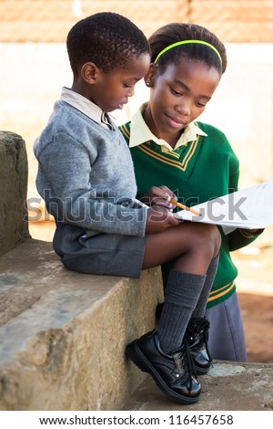 A young lady is helping her little brother with work.