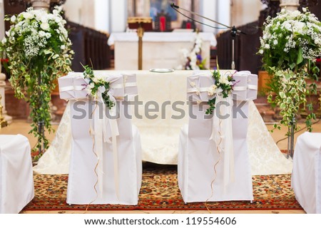 The bride and groom\'s chairs inside of the church.