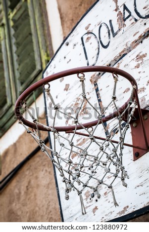 Basketball net situated in a broken and forgotten basketball court.