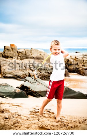 A blond little boy are being photographed on the beach.