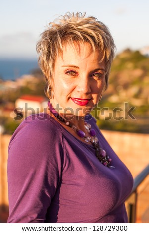 A caucasian woman are being photographed on a balcony in the late afternoon.