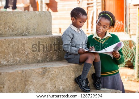 A sister are helping her little  brother with his home work.