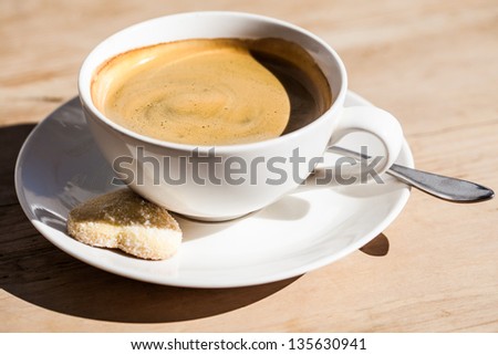 a close-up of a strong black coffee americano with a sugar-coated heart cookie