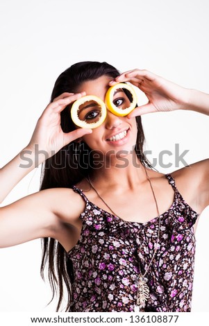 pretty caucasian brunette girl holding hollow lemon peels in front of her eyes smiling