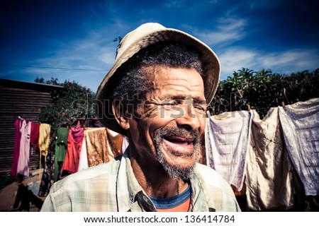 elderly african man in a old khaki hat laughing out loud