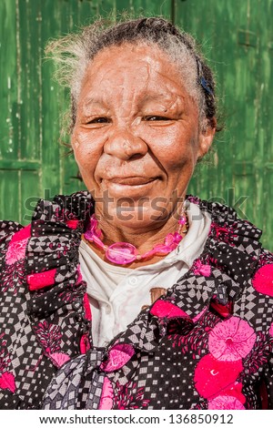 african colored homeless woman in floral shirt and pink jewelry smiling