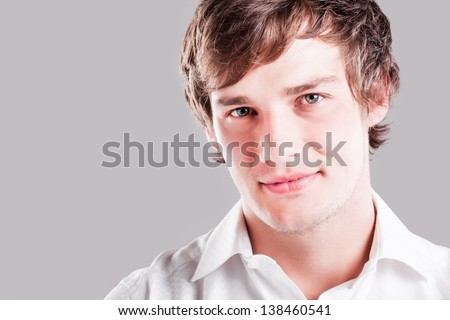 portrait of a handsome caucasian man smiling sweetly with a gray back drop