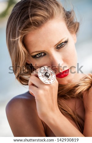 portrait of a beautiful caucasian model with siren red stained lips holding her jeweled hand to her face looking captivating