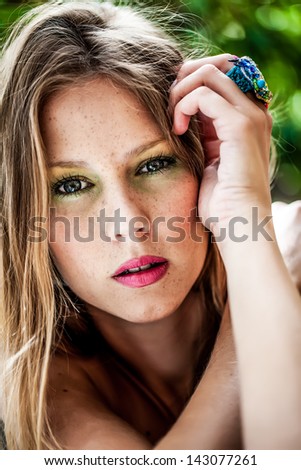 portrait of a caucasian freckled beauty resting her head on her jeweled hand wearing bright magenta lipstick