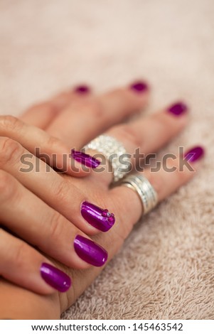 a close-up image of a pair of jeweled hands painted purple with bling on a cream towel