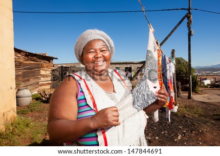 an african woman proudly showing off her clean laundry busy drying on the line outside