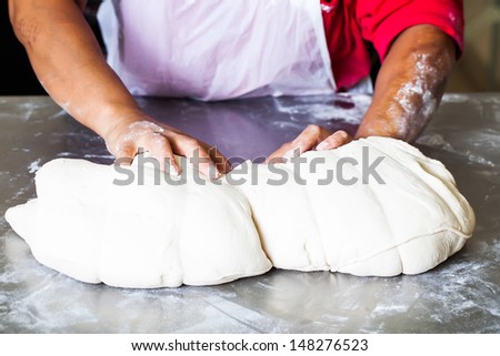 a pair of african hands on a steel table kneading dough