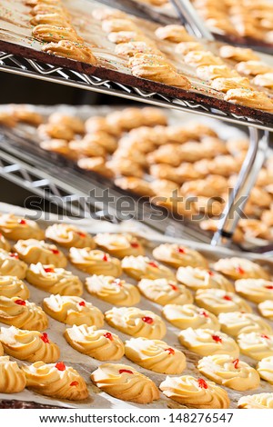 a variety of decorated biscuits cooling off on baking trays in the bakery
