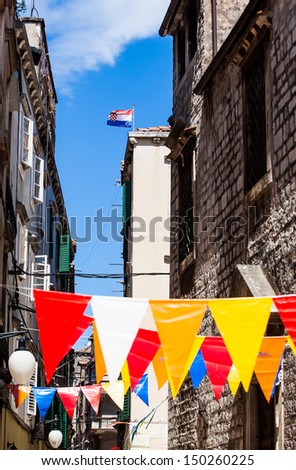 image of colorful plastic flags draped across the narrow streets of the town of Sibenik