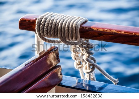 a close-up image of rope knotted to the handle bar on the boat with the blue waters in the background