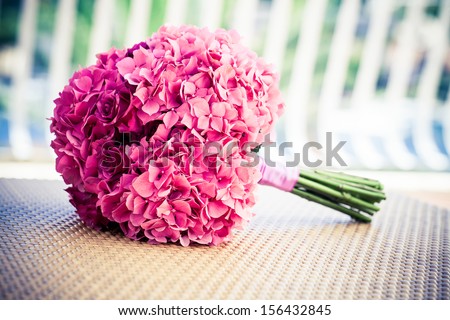 a soft pink hydrangea an rose bridal bouquet resting on a woven surface