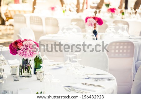 a white crisp decorated table with a pink hydrangea centerpiece and multiple other decorated tables in the background