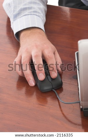 Male hand holding a computer mouse on the wooden desk