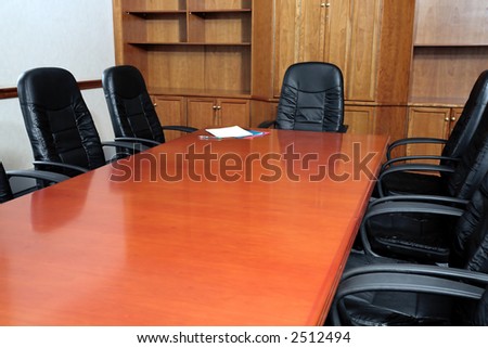 Black leather chairs around a boardroom table with files on the end