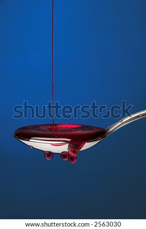 Spoon full of cough medicine over a blue backdrop 3