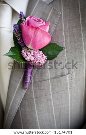 Pink rose boutonniere pinned to a grooms jacket.