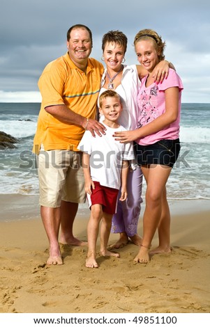 A happy family of mom, dad, sister and brother spending the day at the beach stop the fun and games for a quick portrait
