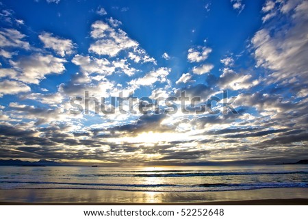 Beautiful sunrise over the ocean with clouds filling up the sky.