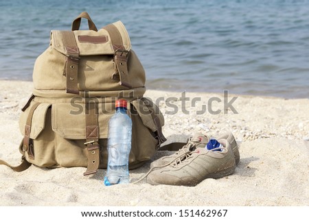 A pair of sneakers, a backpack and a bottle of water on the lake