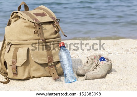 A pair of sneakers, a backpack and a bottle of water on the lake
