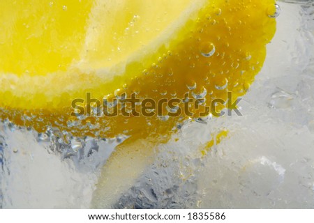 Lemon Wedge in Glass of Cold Mineral Water with Ice. Closeup.